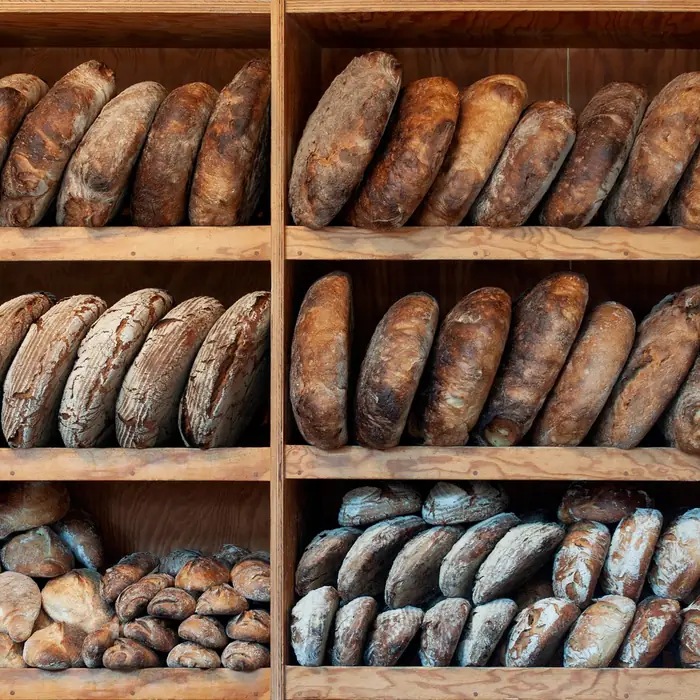 Rows of dark-crusted sourdough loaves on wooden bread shelves